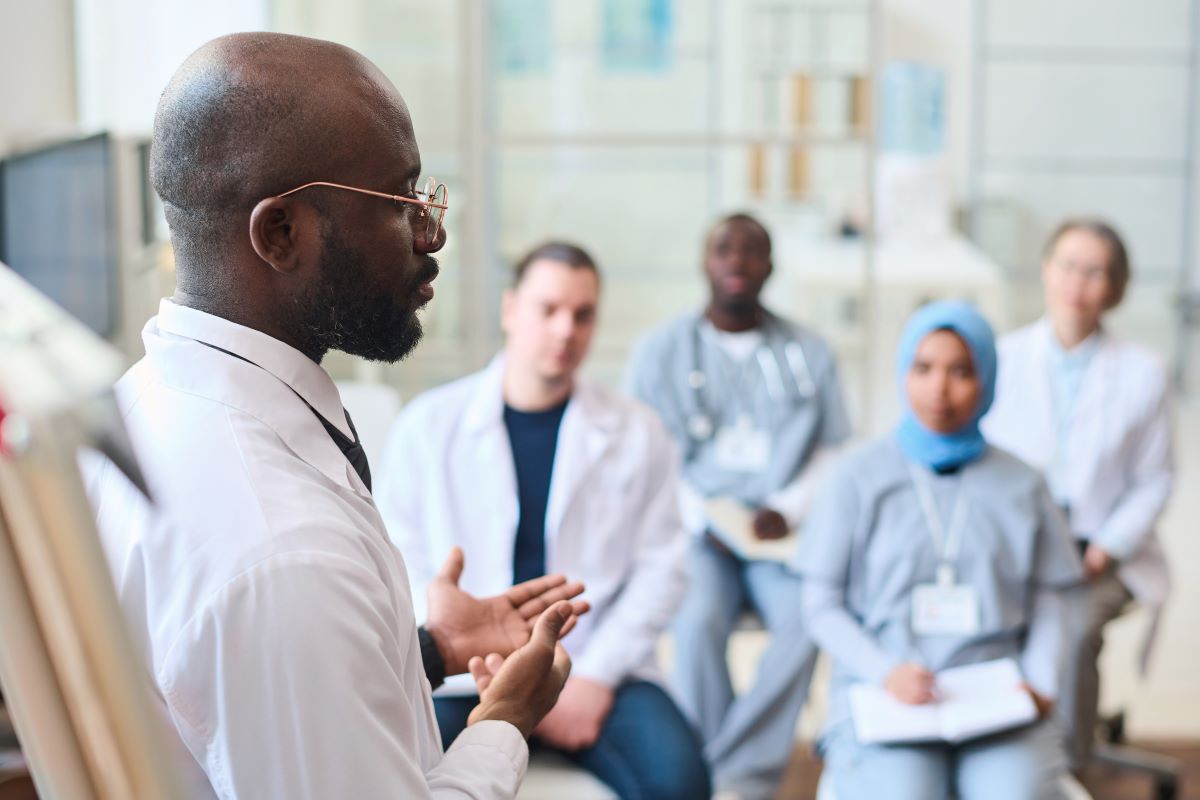 A male healthcare educator working with a group of students