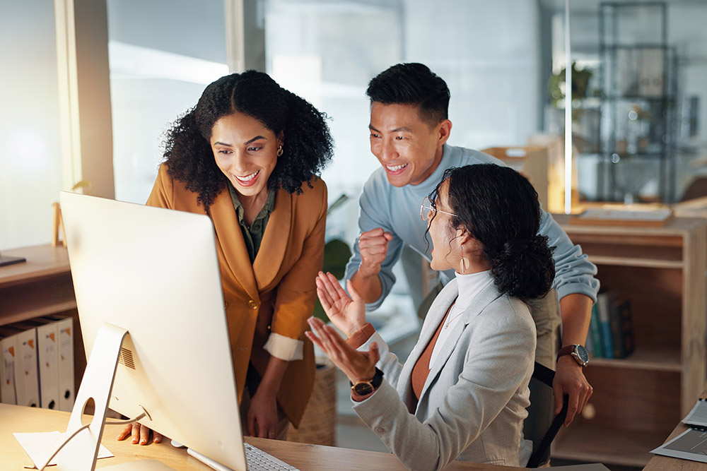 three people standing around computer smiling