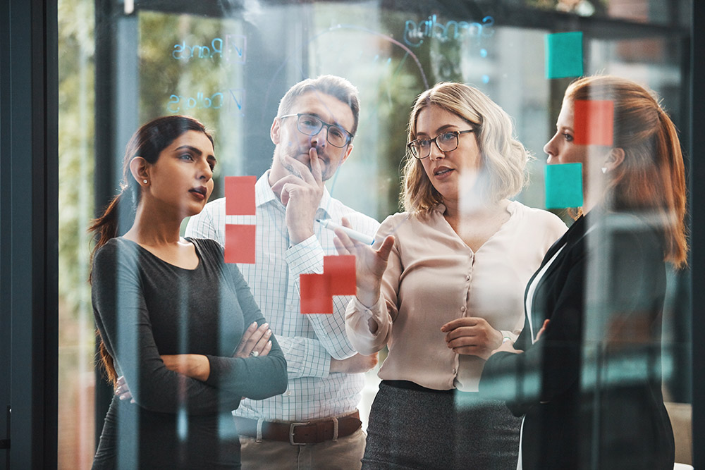people standing in front of glass with post it notes